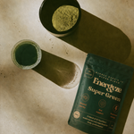 Energyze Super Green powder pouch beside a bowl of green powder and a glass of green drink on a beige surface