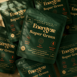 Multiple Energyze Super Green powder pouches arranged on a blurred natural background